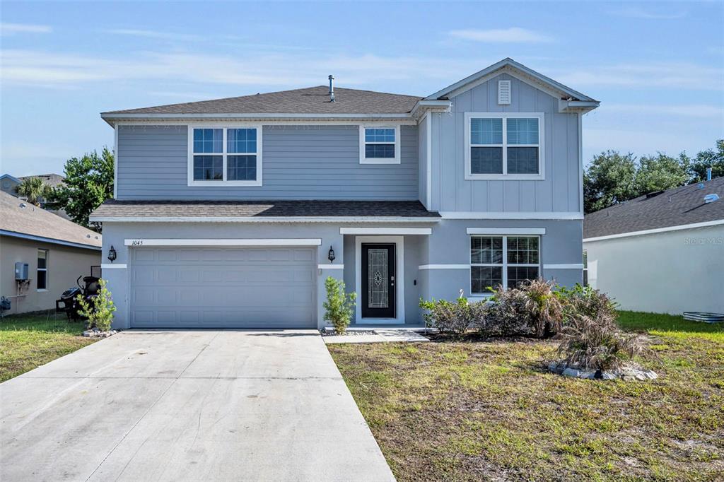 A two-story house with light blue siding, a two-car garage, and a concrete driveway — 1045 BRADFORD RIDGE DRIVE, LEESBURG, FL