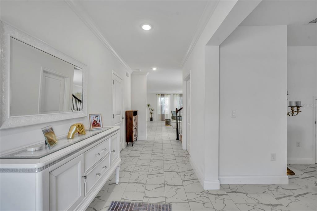 A white hallway features marble-look tile flooring, a mirrored console table, and recessed lighting — 1045 BRADFORD RIDGE DRIVE, LEESBURG, FL