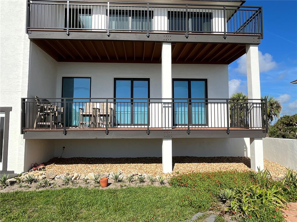 A two-story house exterior features a large wooden deck with black railings and sliding doors — 2139 N OCEAN SHORE BOULEVARD UNIT 2139, FLAGLER BEACH, FL