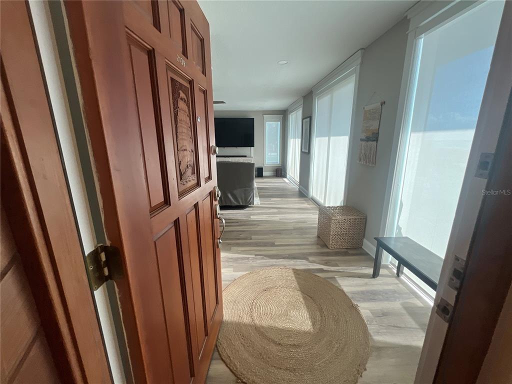 A wooden front door opens into a living area with light wood-look flooring — 2139 N OCEAN SHORE BOULEVARD UNIT 2139, FLAGLER BEACH, FL