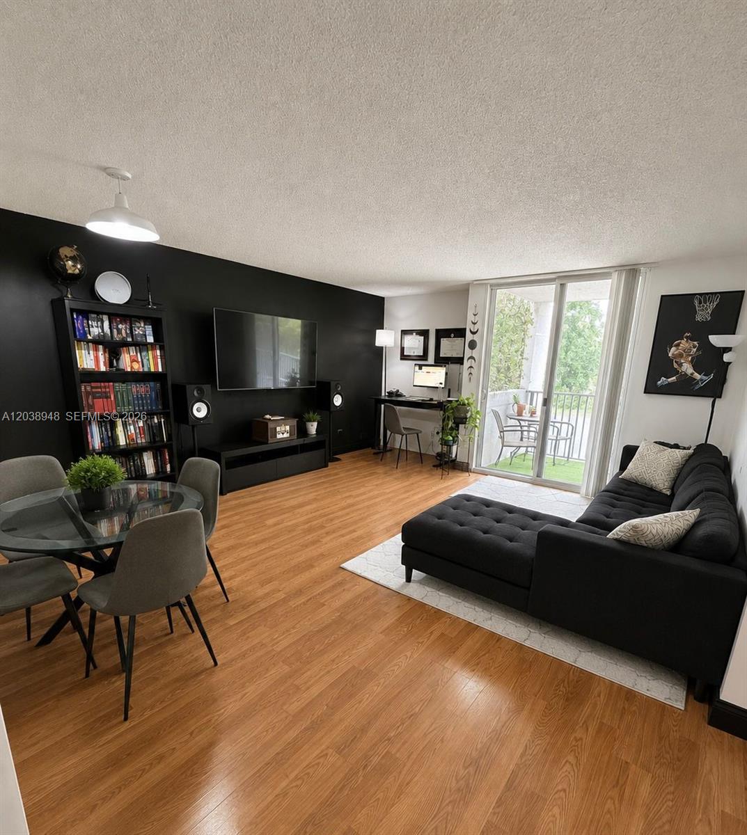 A living room features a black accent wall, wood flooring, a sectional sofa, and a balcony — 800 N Miami Ave # 305, Miami FL 33136, MIAMI, FL