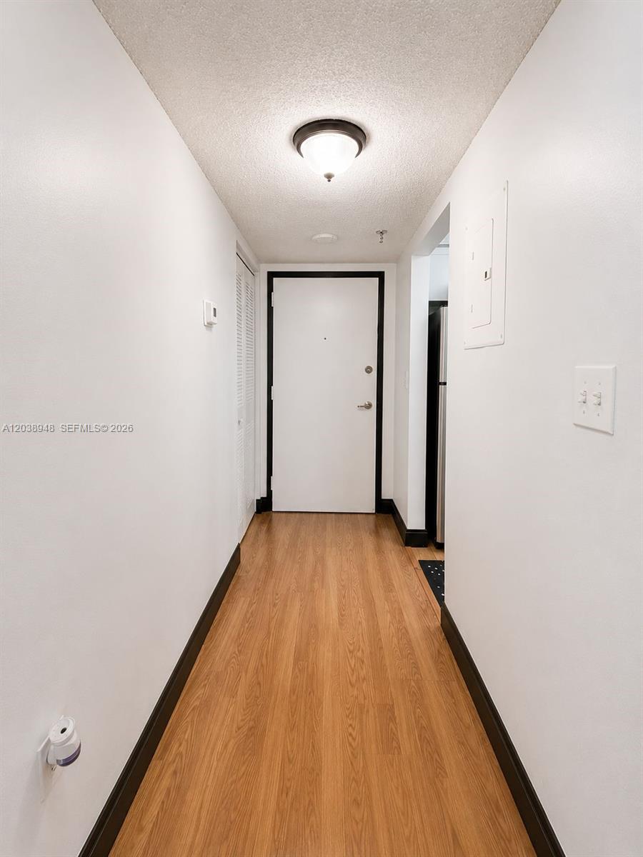 A narrow hallway features light wood-look flooring, white walls, and a single ceiling light fixture — 800 N Miami Ave # 305, Miami FL 33136, MIAMI, FL