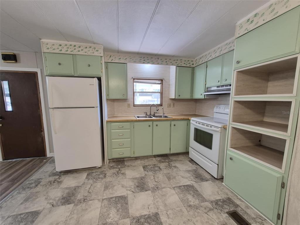 A kitchen with light green cabinets, white appliances, and a checkered tile floor — 18565 SE 24TH LANE, OCKLAWAHA, FL