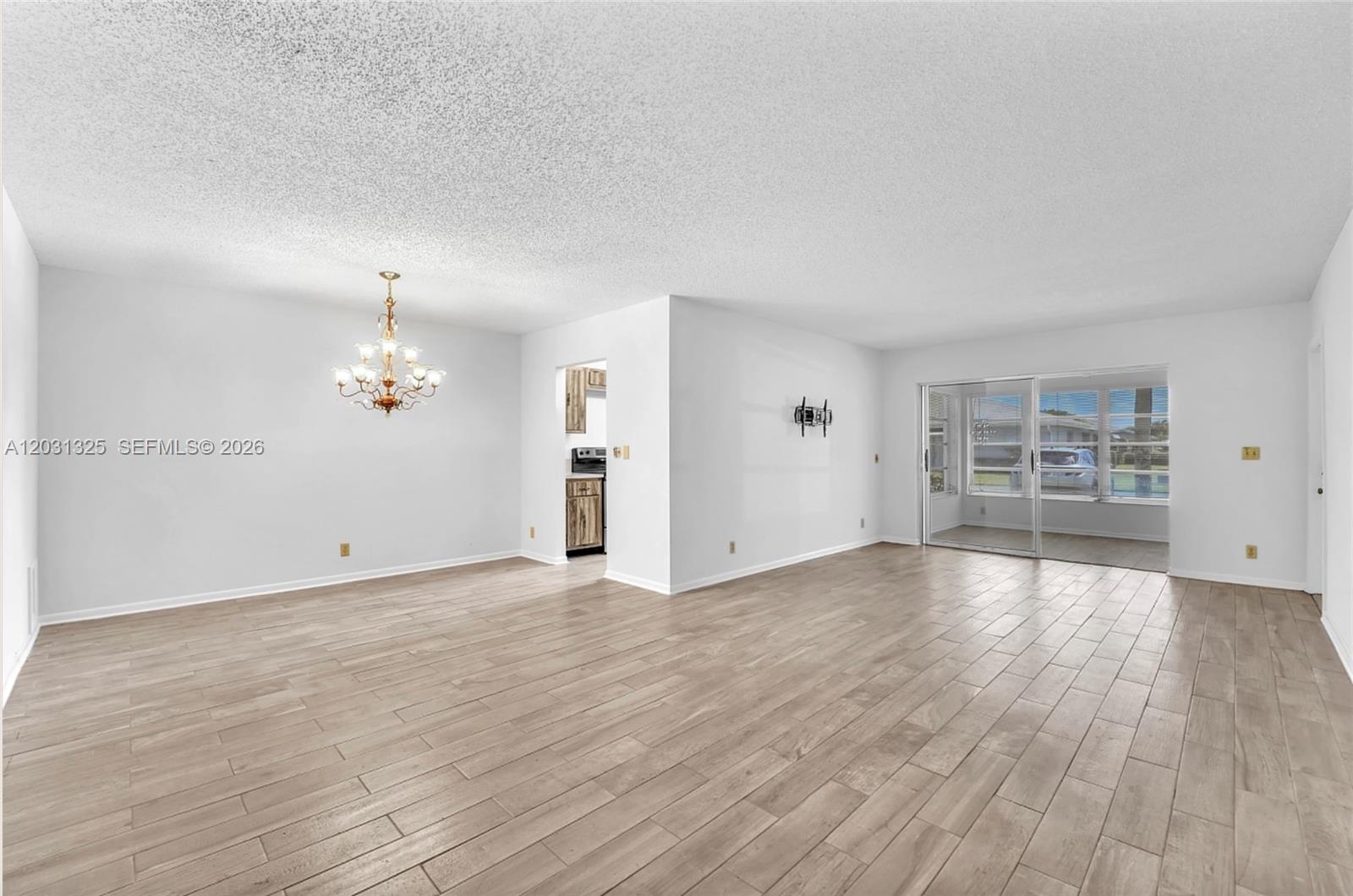 A bright, open-concept living and dining area features white walls and light wood-look tile flooring — 14529 Canalview Dr # B, Delray Beach FL 33484, DELRAY BEACH, FL