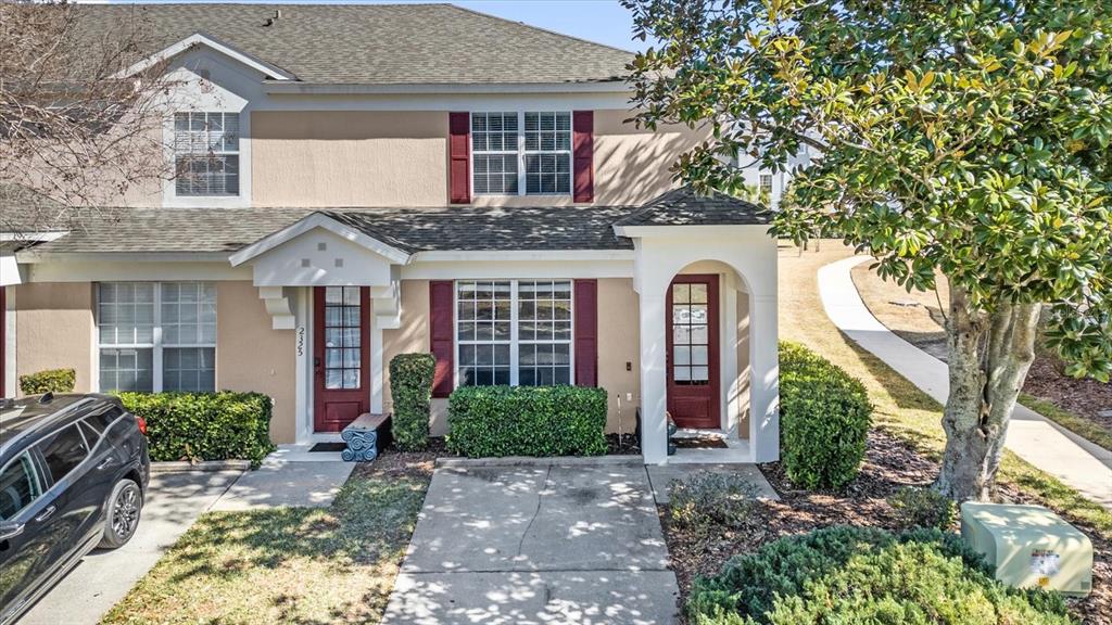 An exterior view of a two-story townhouse with a concrete driveway and a small tree — 2323 SILVER PALM DRIVE, KISSIMMEE, FL
