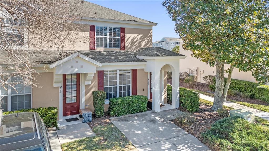 A two-story townhouse exterior features a red front door, tan siding, and a small porch — 2323 SILVER PALM DRIVE, KISSIMMEE, FL