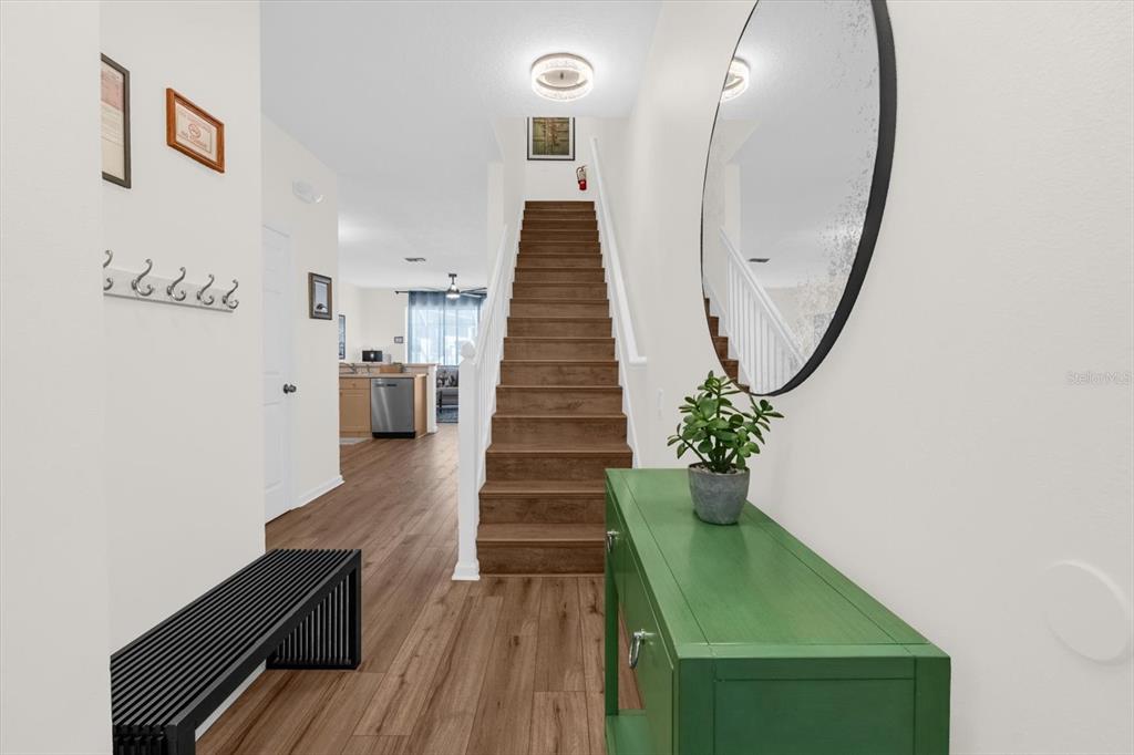A bright entryway features wood-look flooring, a green console table, and stairs leading upward — 2323 SILVER PALM DRIVE, KISSIMMEE, FL