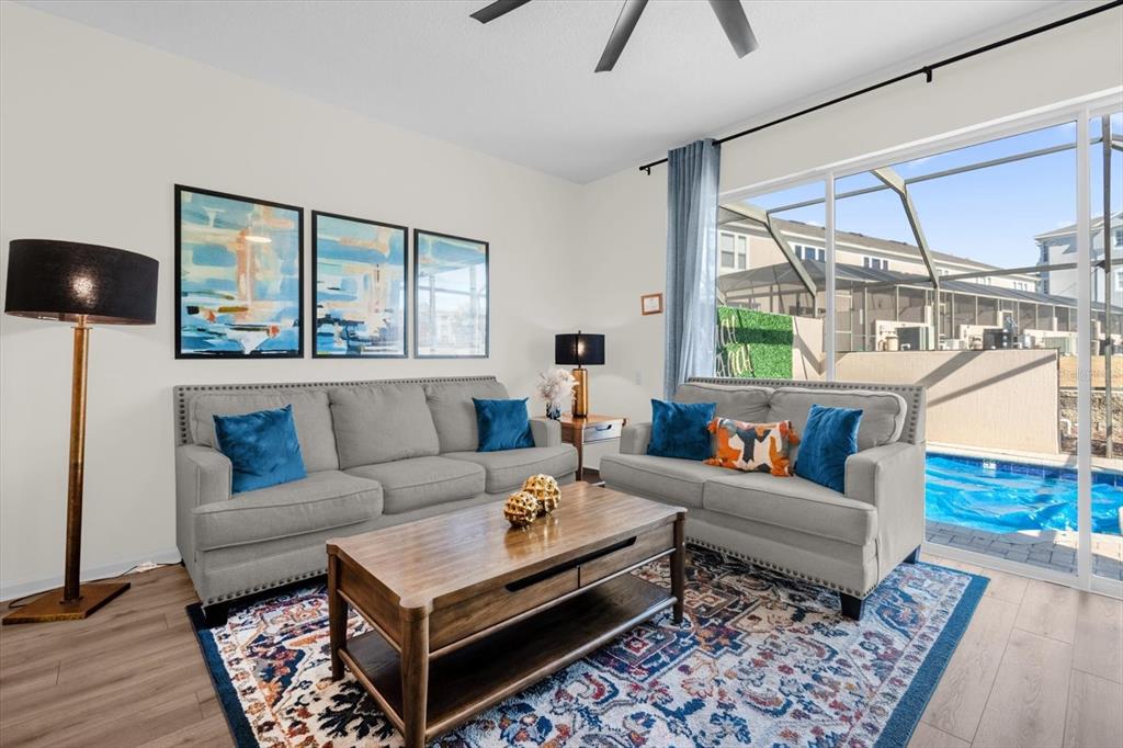 A living room features two gray sofas, a wooden coffee table, and a pool view — 2323 SILVER PALM DRIVE, KISSIMMEE, FL