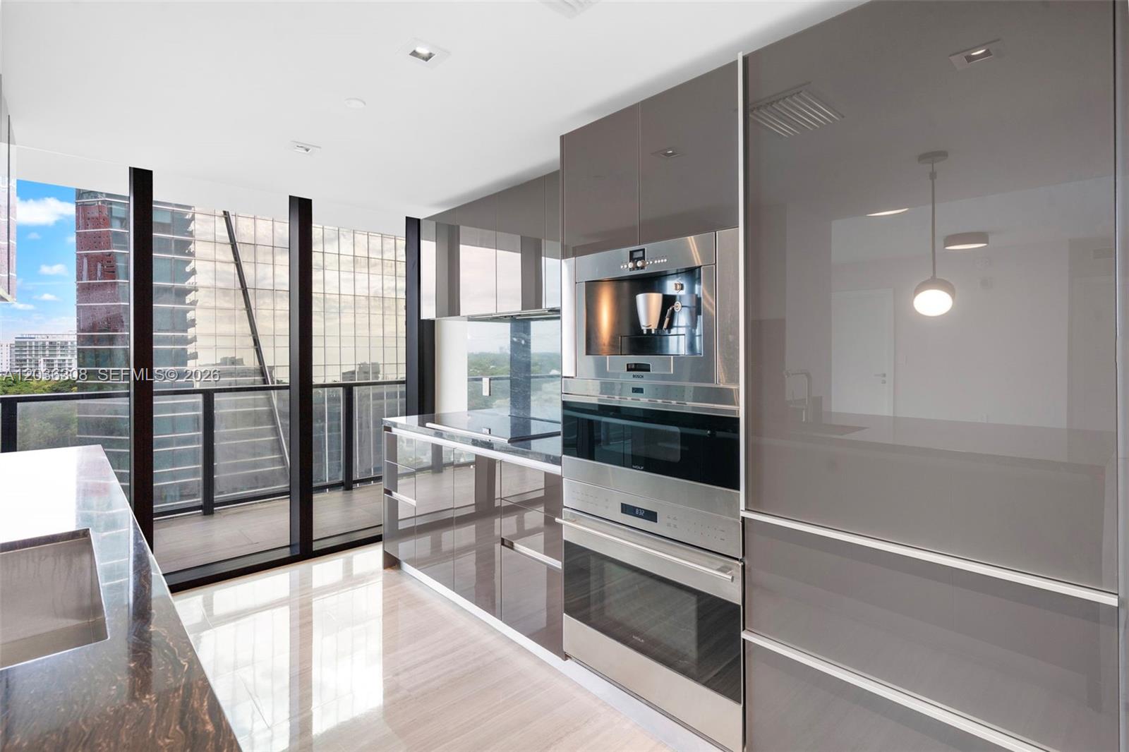A modern kitchen features glossy grey cabinetry, stainless steel built-in appliances, and floor-to-ceiling windows — 1451 Brickell Ave # 1005, Miami FL 33131, MIAMI, FL