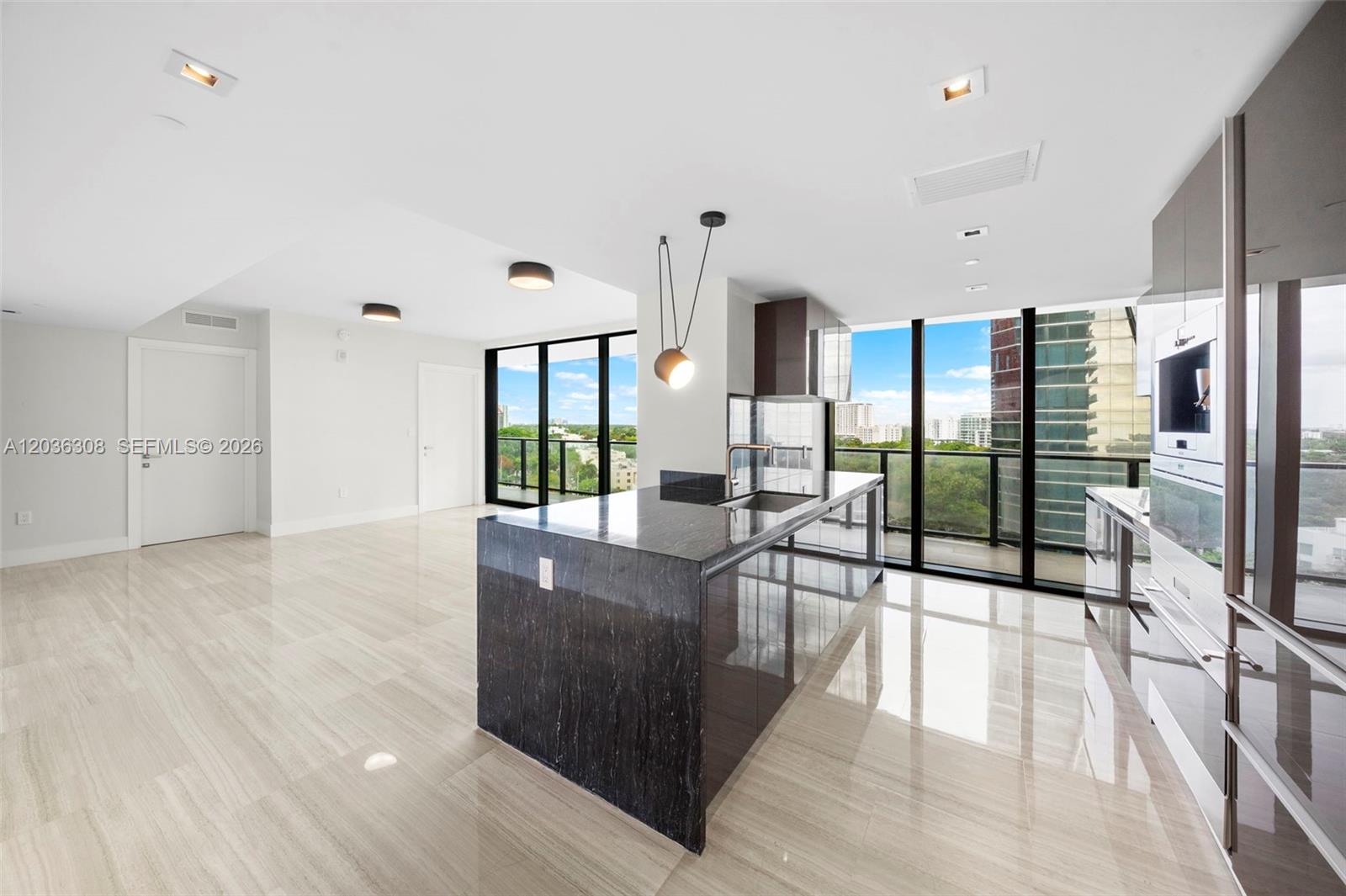 A modern kitchen features a dark stone island, glossy cabinets, and floor-to-ceiling windows — 1451 Brickell Ave # 1005, Miami FL 33131, MIAMI, FL