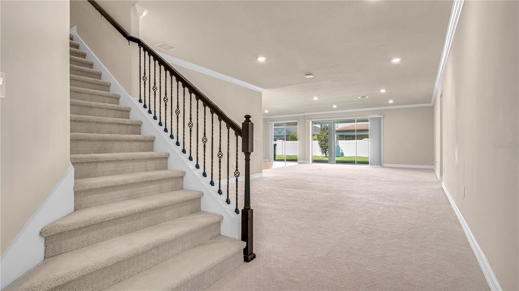 A carpeted staircase with a dark metal railing leads to an open living area — 9212 HANGING VINE COURT, ORLANDO, FL
