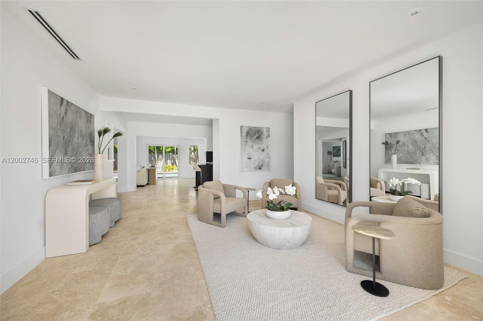 A bright living room features beige armchairs, a round coffee table, and two large wall mirrors — 255 Ridgewood Rd, Key Biscayne FL 33149, KEY BISCAYNE, FL