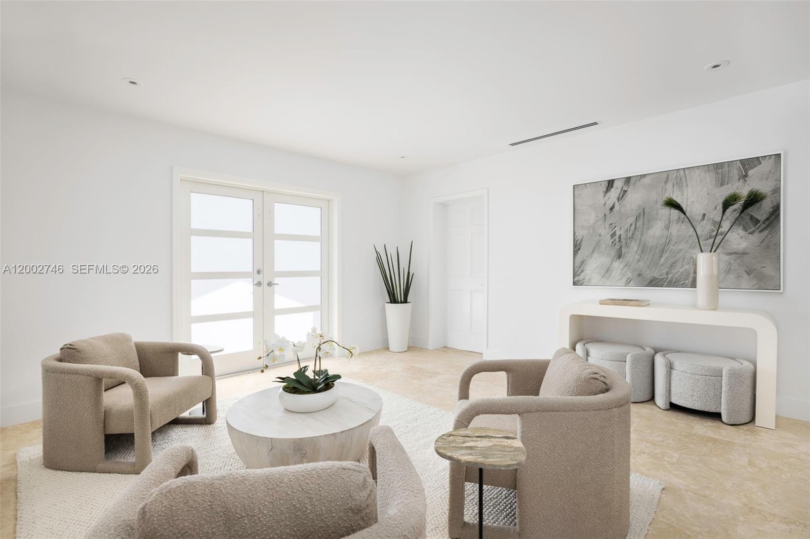 A bright living room features beige armchairs, a round coffee table, and a console table — 255 Ridgewood Rd, Key Biscayne FL 33149, KEY BISCAYNE, FL