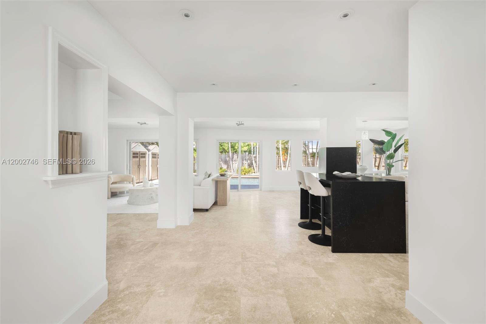 A bright, open-concept living area features light tile flooring and a black kitchen island — 255 Ridgewood Rd, Key Biscayne FL 33149, KEY BISCAYNE, FL