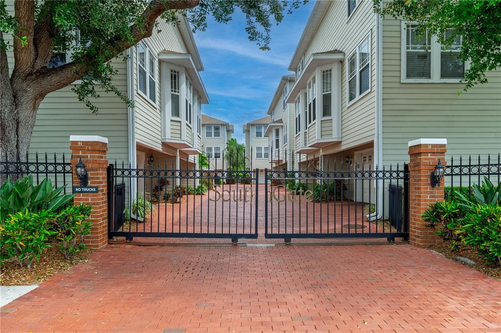 A gated entrance with brick pillars leads to a paved courtyard between two residential buildings — 3315 W DE LEON STREET UNIT 15, TAMPA, FL