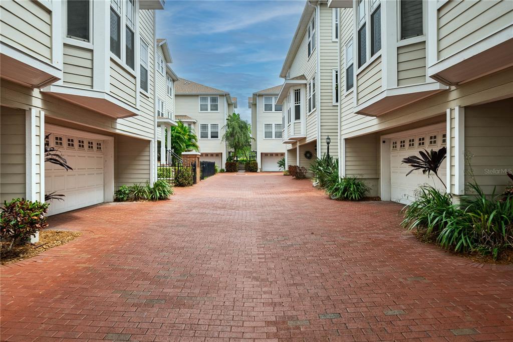 A brick-paved driveway leads between two multi-story residential buildings with attached garages — 3315 W DE LEON STREET UNIT 15, TAMPA, FL