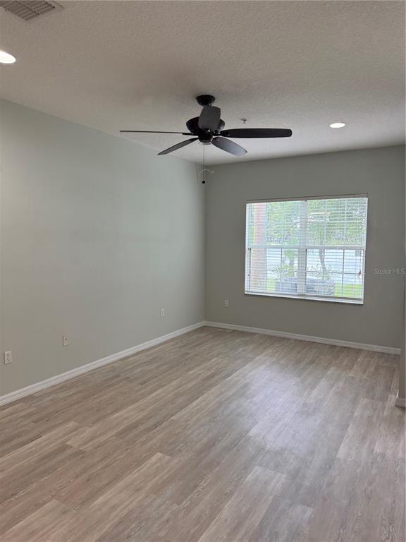 An empty room features light-colored wood-look flooring, a ceiling fan, and a window with blinds — 2530 PASSAMONTE DRIVE UNIT 10E, WINTER PARK, FL