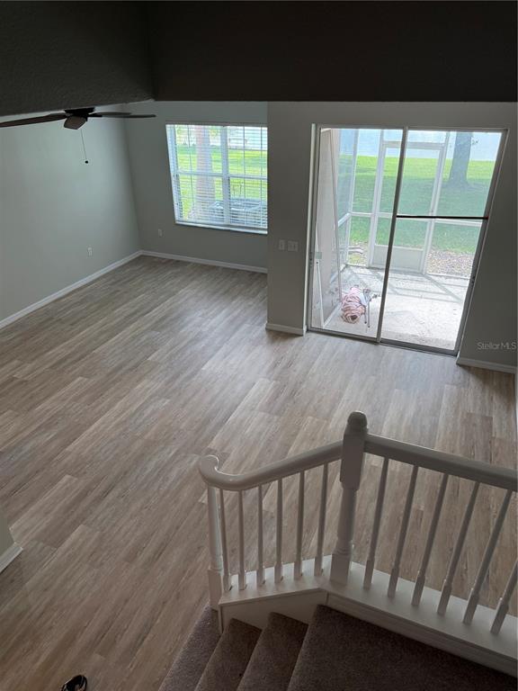 An elevated view of a living room with wood-look flooring, a ceiling fan, and sliding doors — 2530 PASSAMONTE DRIVE UNIT 10E, WINTER PARK, FL