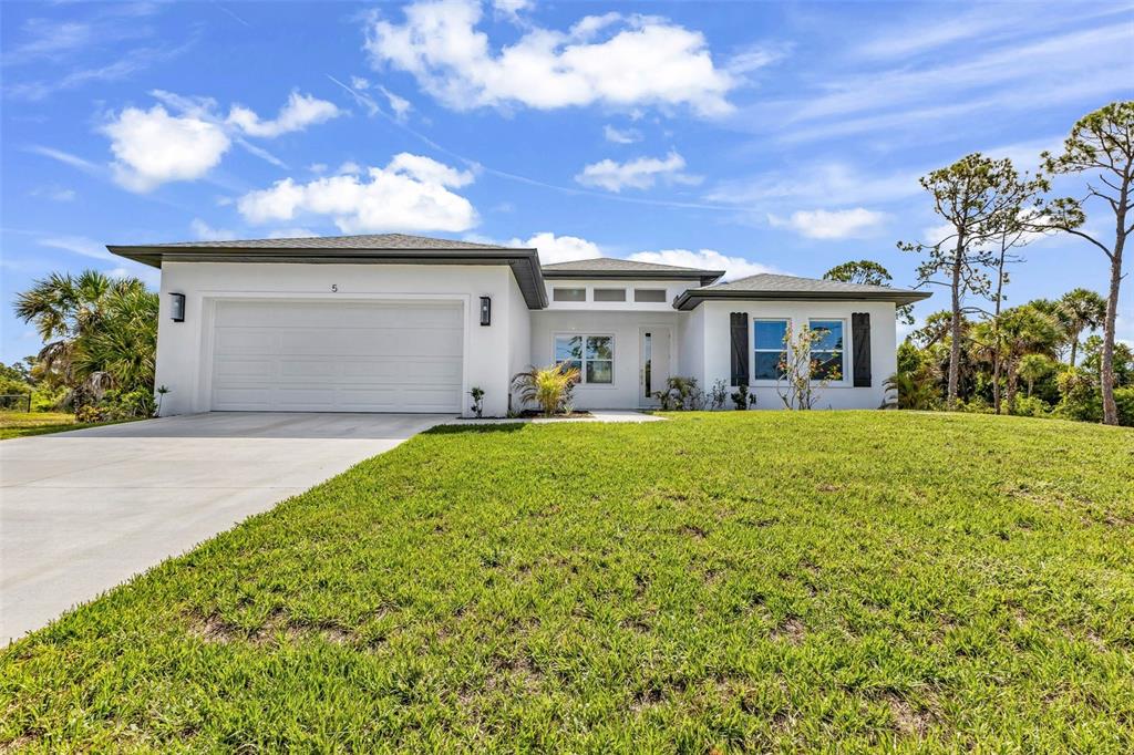 A single-story white house with a two-car garage and a large front lawn — 5 MATE DRIVE, PLACIDA, FL