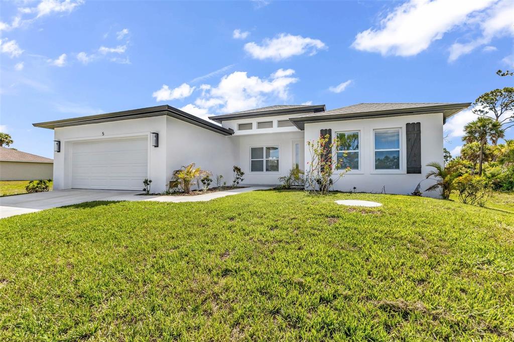 A white, single-story house with a two-car garage and a green lawn under blue skies — 5 MATE DRIVE, PLACIDA, FL