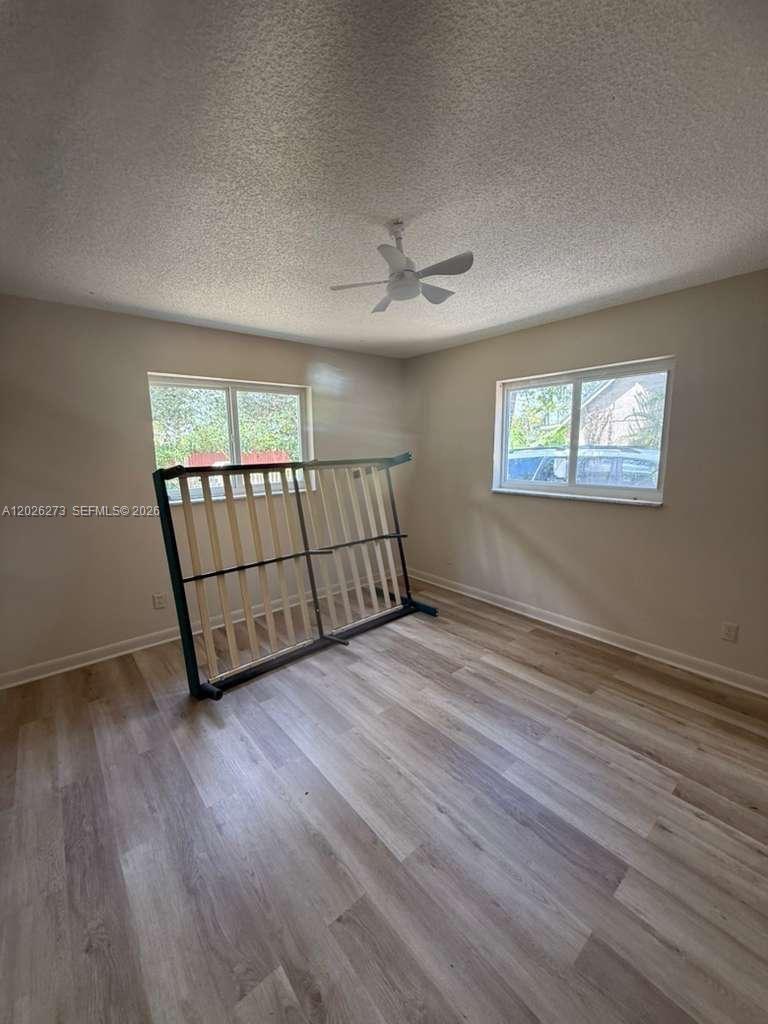 An empty bedroom features light wood-look flooring, beige walls, and a ceiling fan — 3850 SW 59th Ter, Davie FL 33314, DAVIE, FL