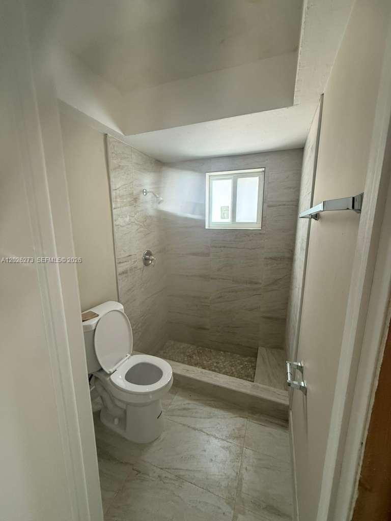 A bathroom features a walk-in shower with stone-look tile and a white toilet — 3850 SW 59th Ter, Davie FL 33314, DAVIE, FL