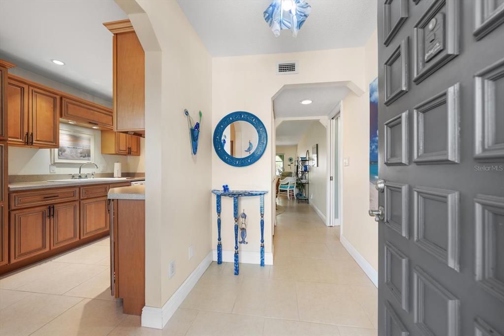 An entryway with tile flooring leads to a kitchen with wood cabinets and a hallway — 1005 CORDOVA GREEN, SEMINOLE, FL