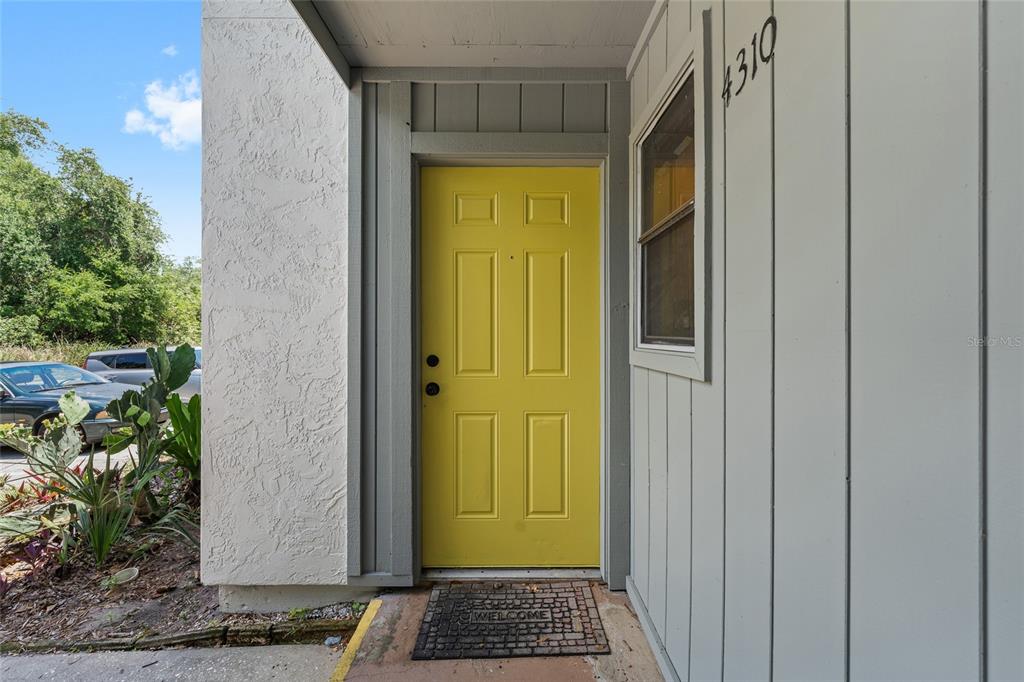 A bright yellow front door is set into a gray exterior wall with a window — 4310 LAKEWAY DRIVE UNIT 12B, ORLANDO, FL