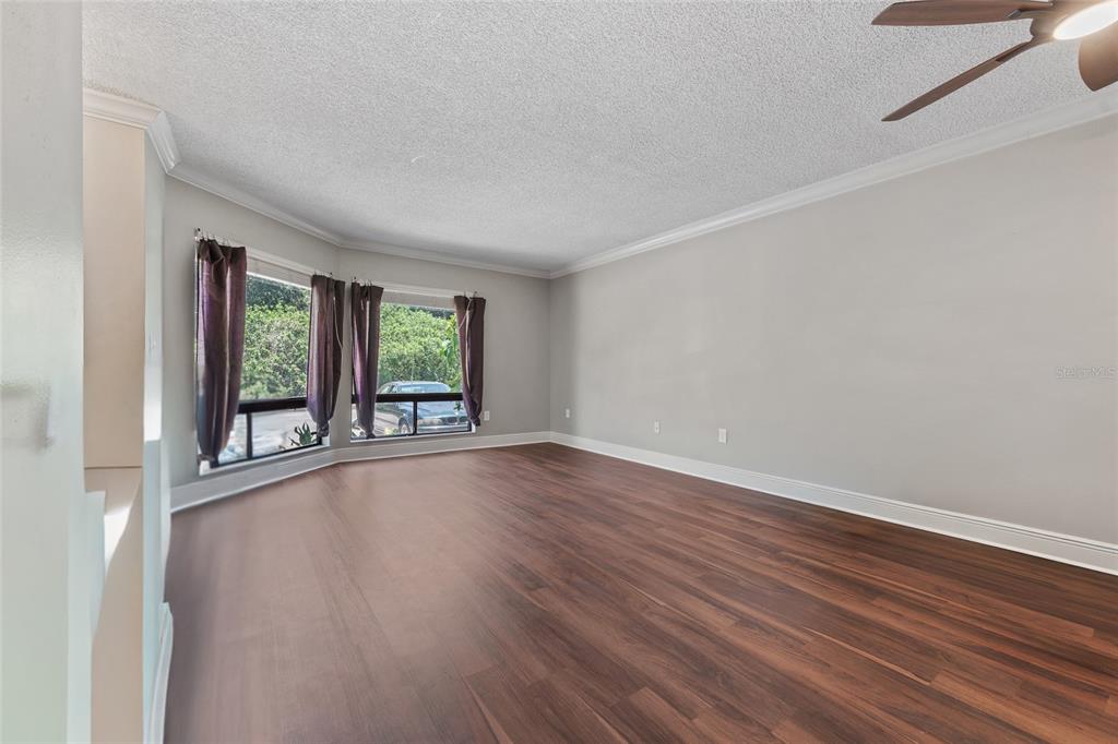 An empty room with dark wood-look flooring, light gray walls, and a bay window — 4310 LAKEWAY DRIVE UNIT 12B, ORLANDO, FL