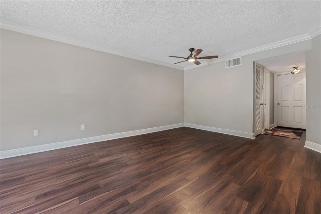 An empty room with dark wood-look flooring, light gray walls, and a ceiling fan — 4310 LAKEWAY DRIVE UNIT 12B, ORLANDO, FL
