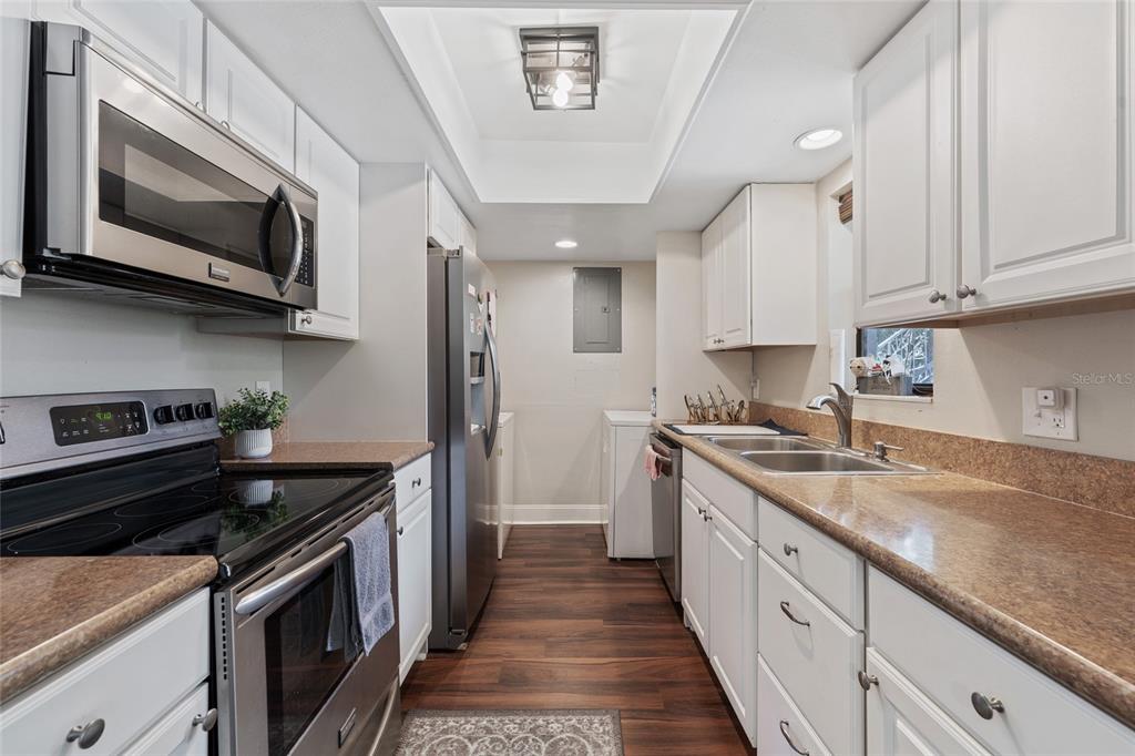 A galley kitchen features white cabinets, stainless steel appliances, and brown laminate countertops — 4310 LAKEWAY DRIVE UNIT 12B, ORLANDO, FL