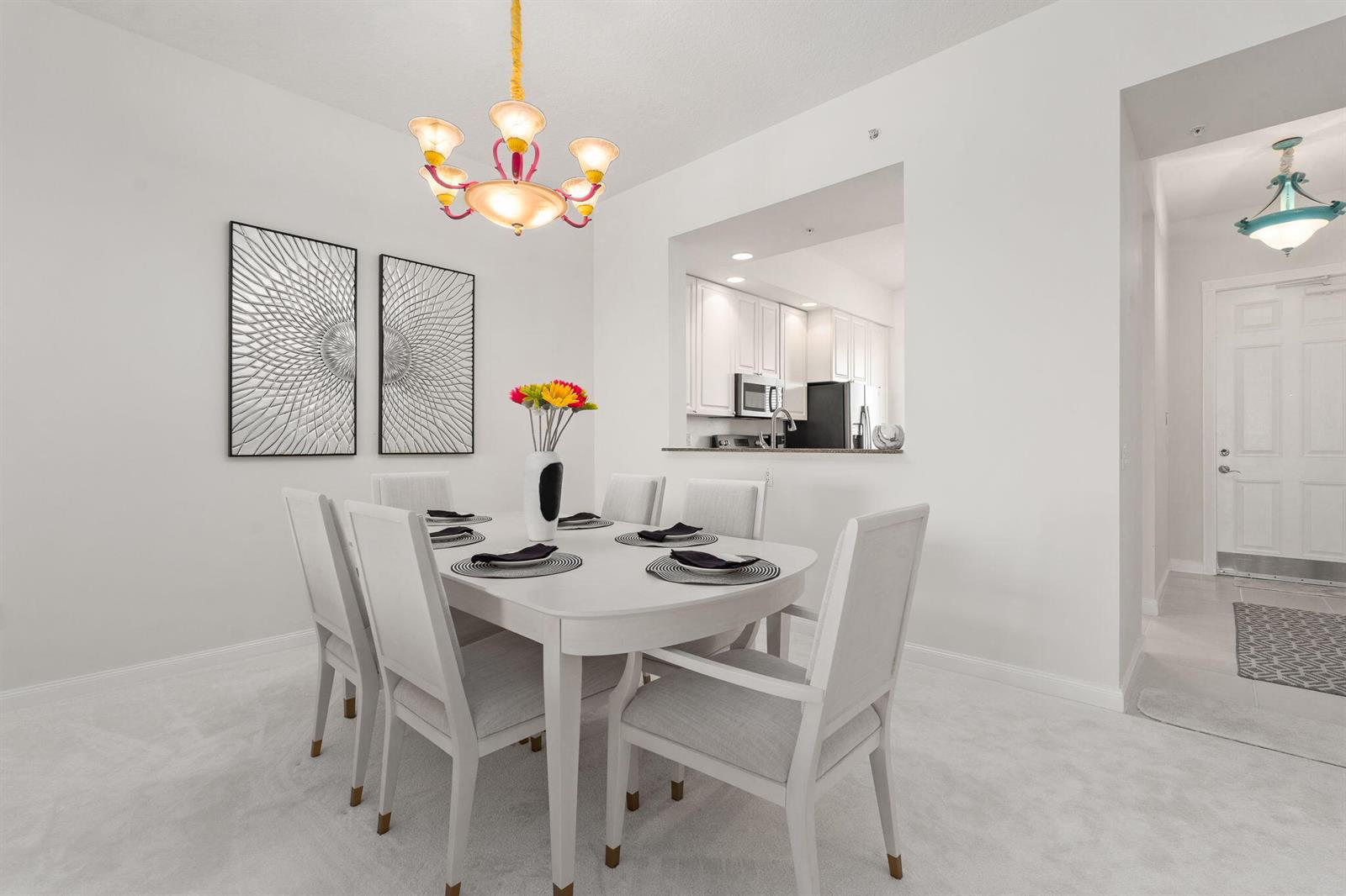 A dining room with a white table, six chairs, a chandelier, and a kitchen pass-through — 14 Harbour Isle Drive W, Fort Pierce FL 34949, FORT PIERCE, FL