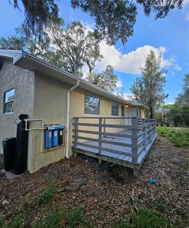 A house exterior features a wooden deck, a water filtration system, and a black tank — 7237 HILLCREST STREET, LEESBURG, FL