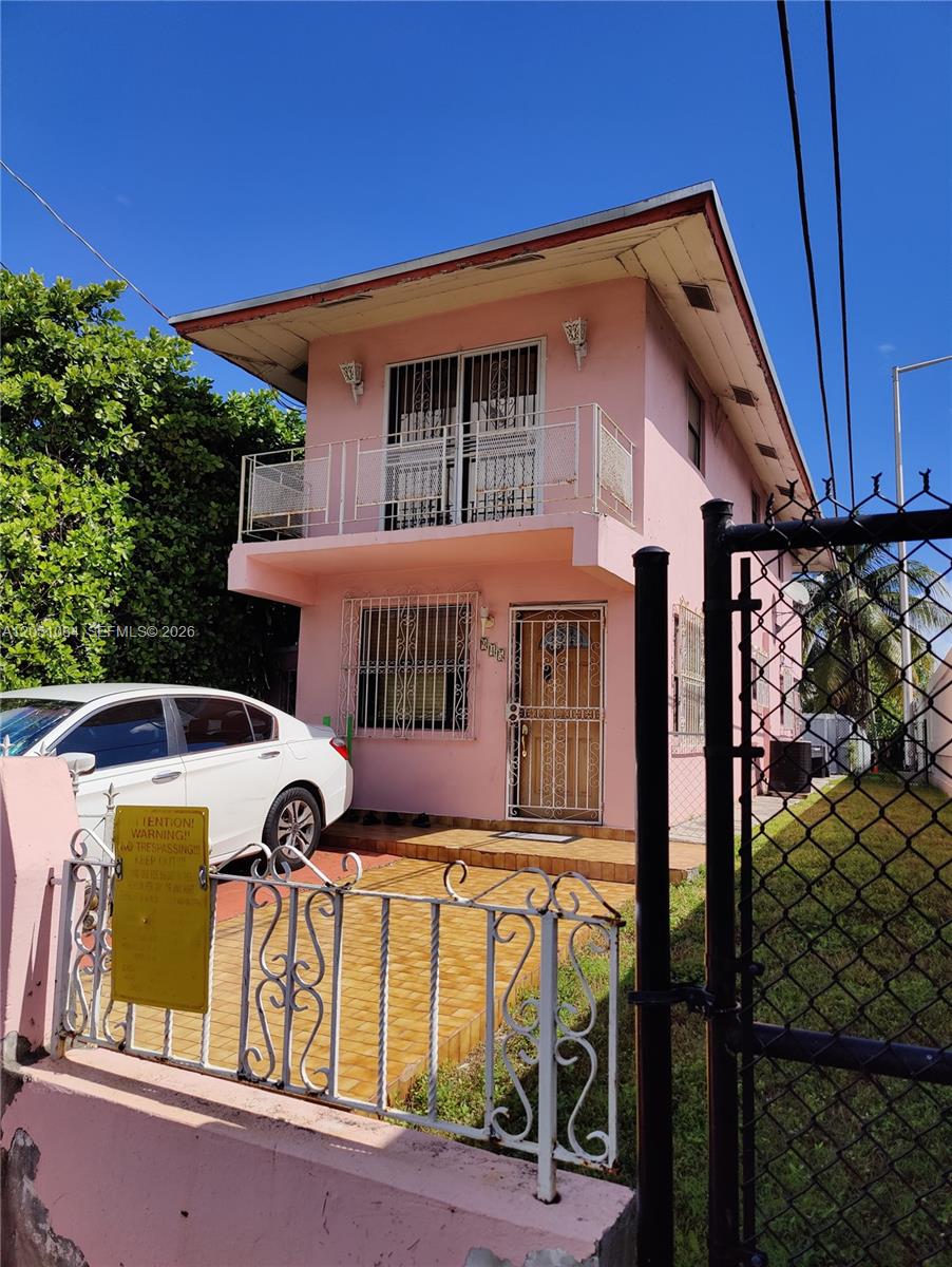A two-story pink house with a balcony, security bars, and a paved front yard — 945 NW 19th Ave, Miami FL 33125, MIAMI, FL