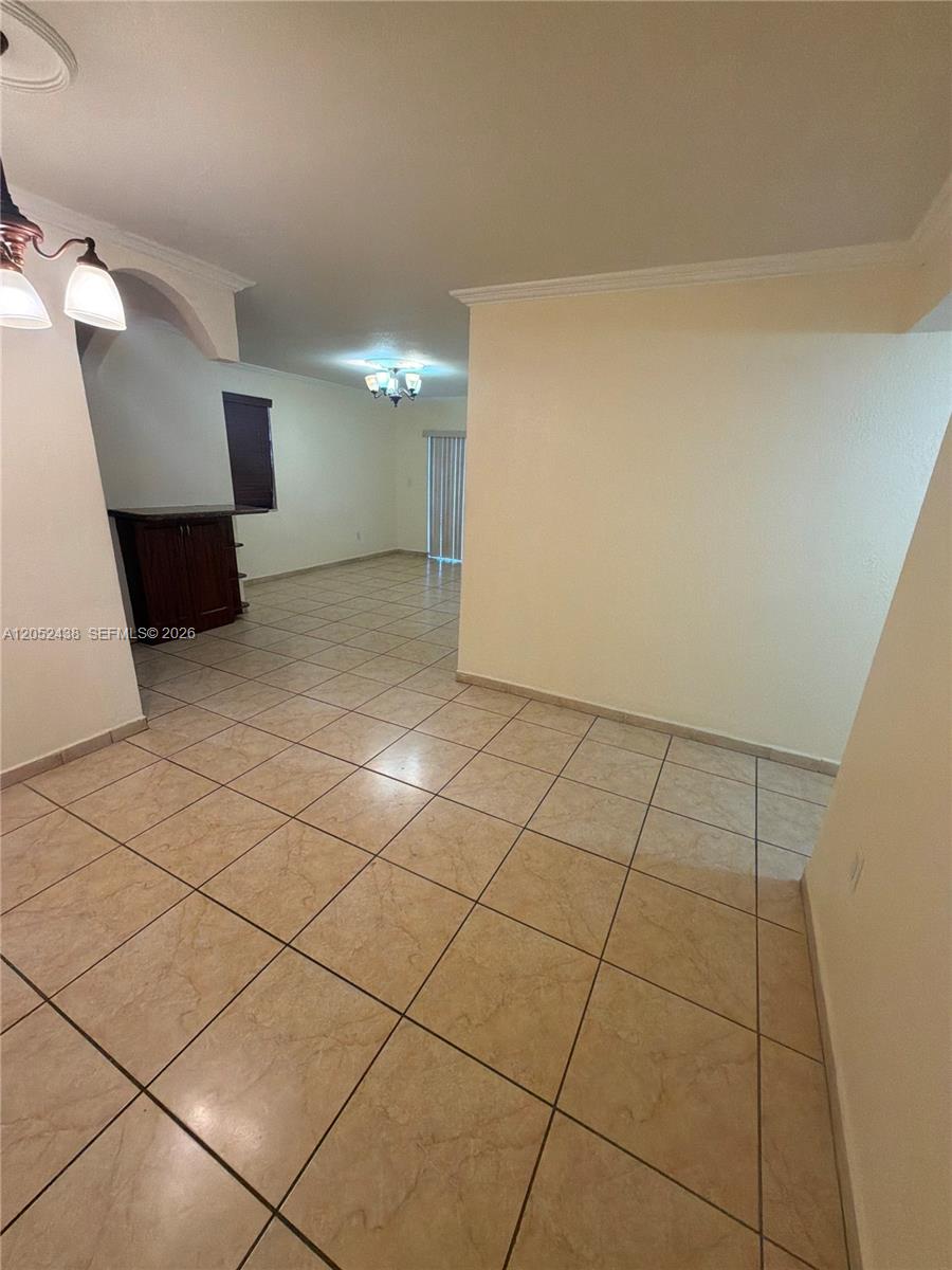 A tiled living area features a dark wood cabinet and a sliding glass door — 1101 SW 122nd Ave # 106, Miami FL 33184, MIAMI, FL