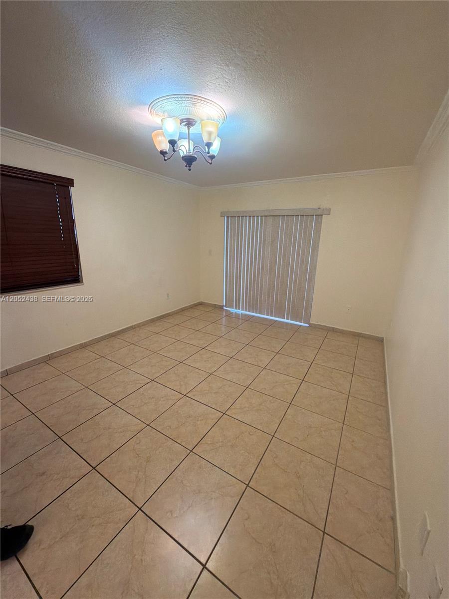 An empty room features beige tile flooring, a ceiling light fixture, and vertical window blinds — 1101 SW 122nd Ave # 106, Miami FL 33184, MIAMI, FL