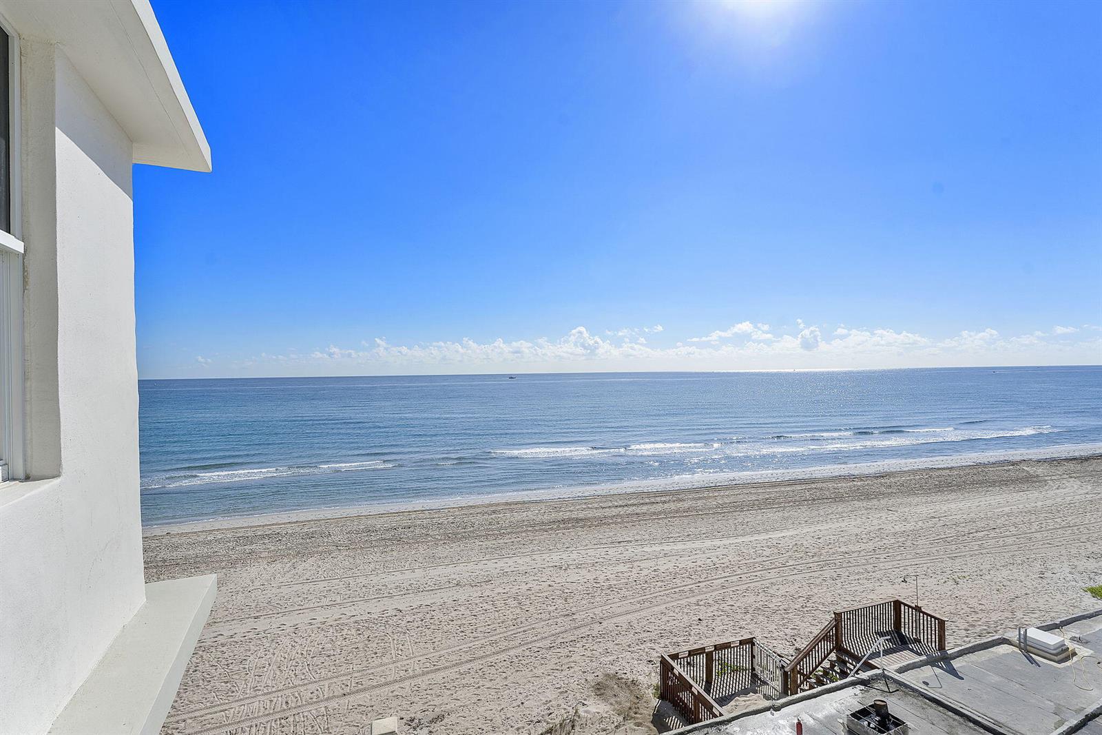 An elevated view shows a sandy beach and ocean from a white building balcony — 4505 S Ocean Boulevard # 307, Highland Beach FL 33487, HIGHLAND BEACH, FL