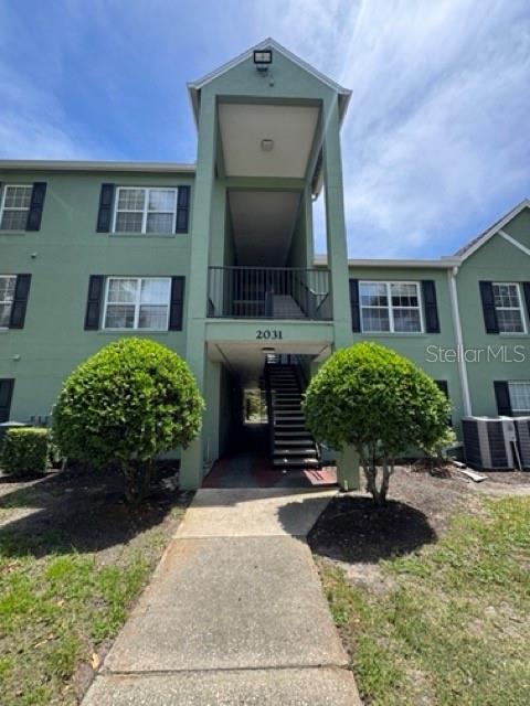 A green multi-story apartment building features a central staircase and two rounded bushes in front — 2031 DIXIE BELLE DRIVE UNIT 2031L, ORLANDO, FL