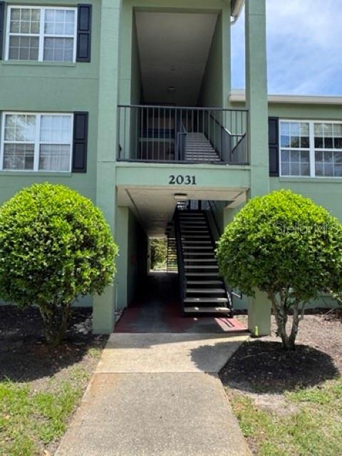 An exterior view of a two-story apartment building with a central staircase and green siding — 2031 DIXIE BELLE DRIVE UNIT 2031L, ORLANDO, FL