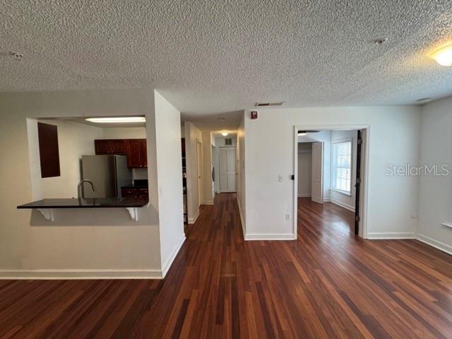 A kitchen with a breakfast bar opens into a living area with hardwood floors — 2031 DIXIE BELLE DRIVE UNIT 2031L, ORLANDO, FL