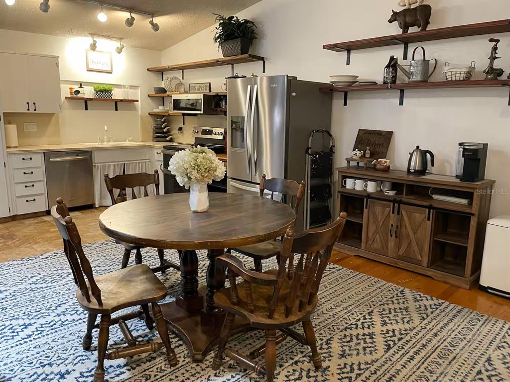 A cluttered garage features two wooden shelving units, storage bins, and a rolling utility cart — 2107 GROVE VALLEY, PALM HARBOR, FL