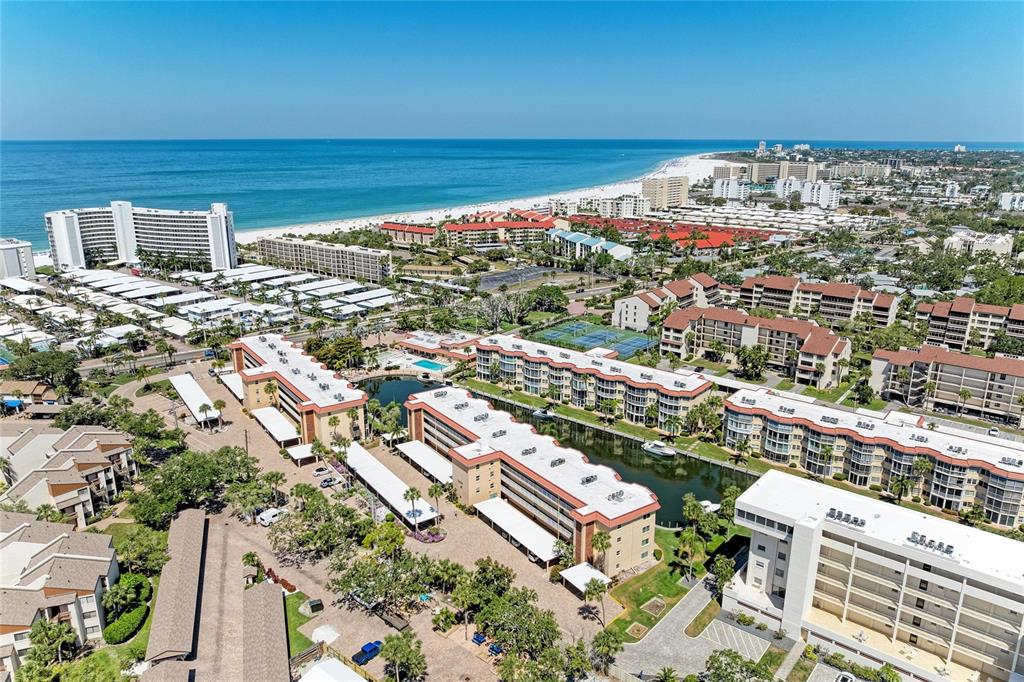 An aerial view of a coastal resort complex featuring multiple buildings, a canal, and beach — 1257 S PORTOFINO DRIVE UNIT 104, SARASOTA, FL
