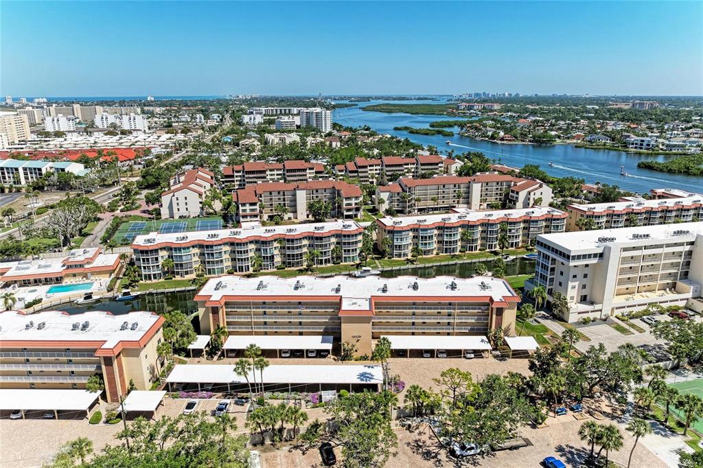 An aerial view shows several multi-story apartment buildings surrounded by palm trees and a waterway — 1257 S PORTOFINO DRIVE UNIT 104, SARASOTA, FL