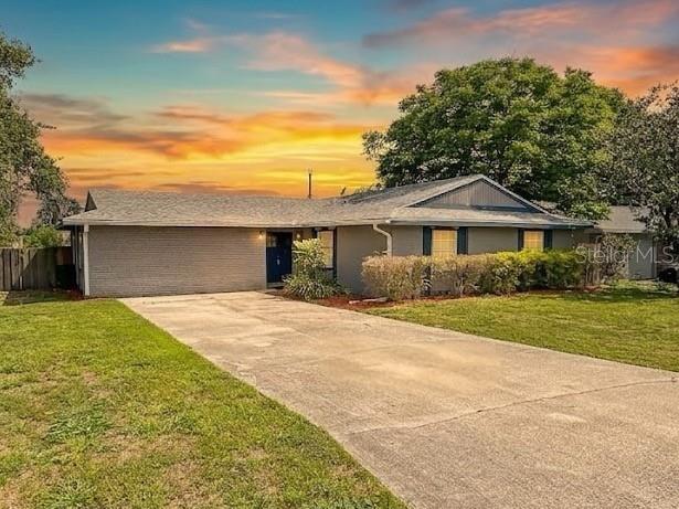 A single-story gray brick house with a concrete driveway under a sunset sky — 2802 CHRISTIE LANE, LAKELAND, FL