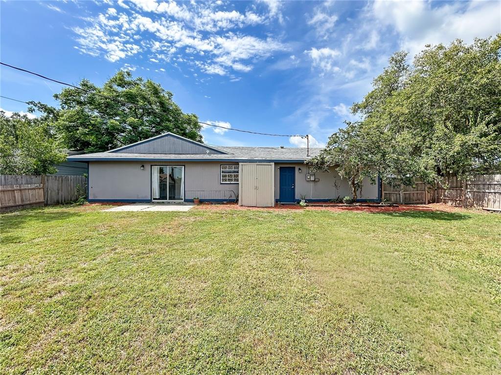 The rear exterior of a single-story house features a gray facade, sliding glass doors, and a shed — 2802 CHRISTIE LANE, LAKELAND, FL