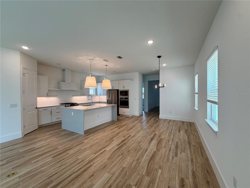 A modern kitchen features white cabinetry, a central island, and wood-look tile flooring — 12438 CLEAR SAPPHIRE DRIVE, WINTER GARDEN, FL