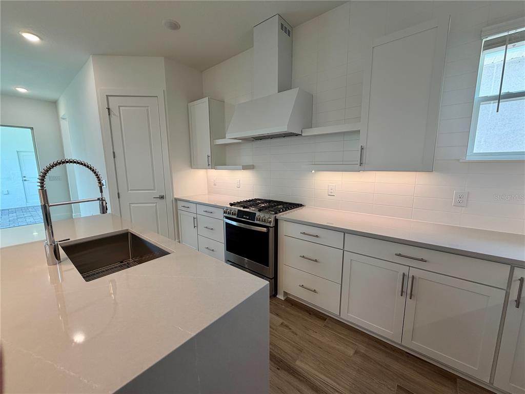 A modern kitchen features white cabinetry, a central island with a sink, and stainless appliances — 12438 CLEAR SAPPHIRE DRIVE, WINTER GARDEN, FL