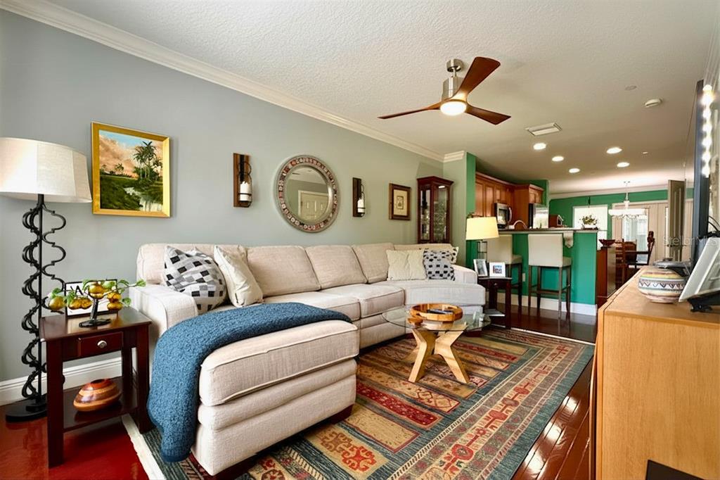 A living room with a sectional sofa, patterned rug, and an open kitchen in the background — 4853 TUSCAN LOON DRIVE, TAMPA, FL