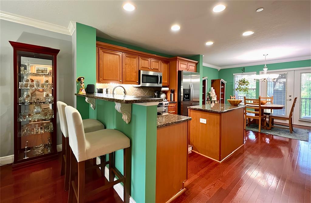 A kitchen features green walls, wood cabinets, granite countertops, and a central island — 4853 TUSCAN LOON DRIVE, TAMPA, FL