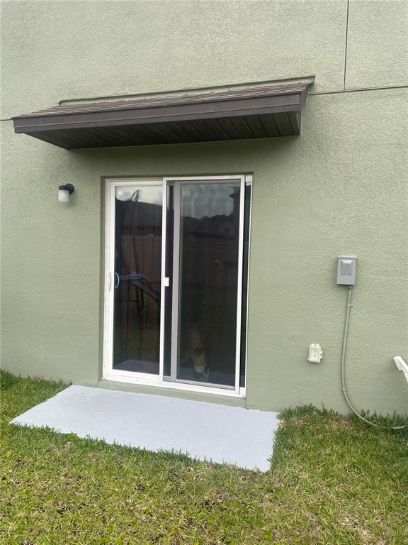 A sliding glass door with a brown awning sits on a concrete patio outside — 1541 LANDMARK DRIVE, LAKELAND, FL